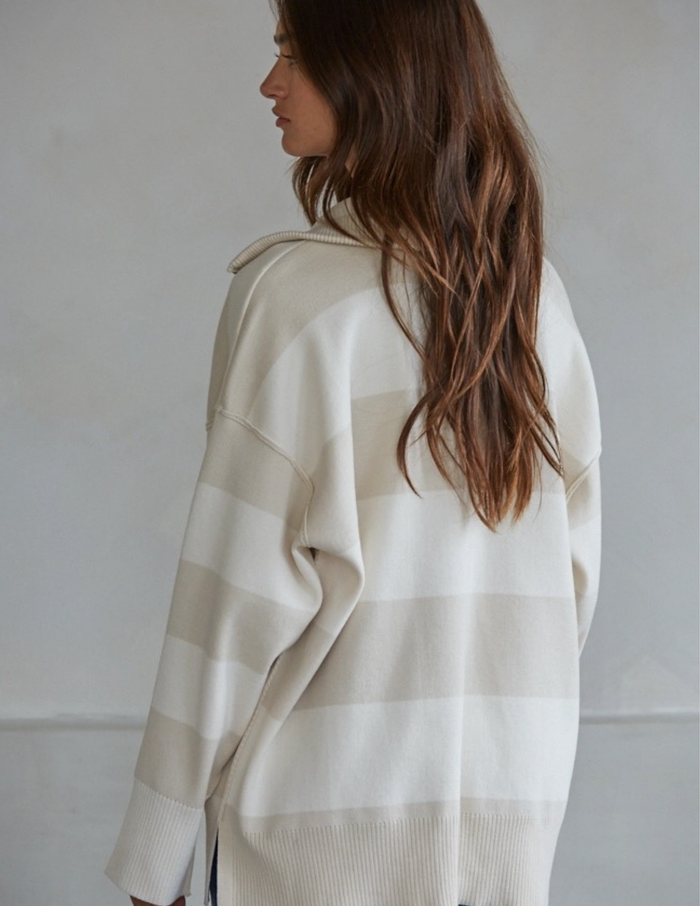 Woman wearing a white striped sweater against a plain background
