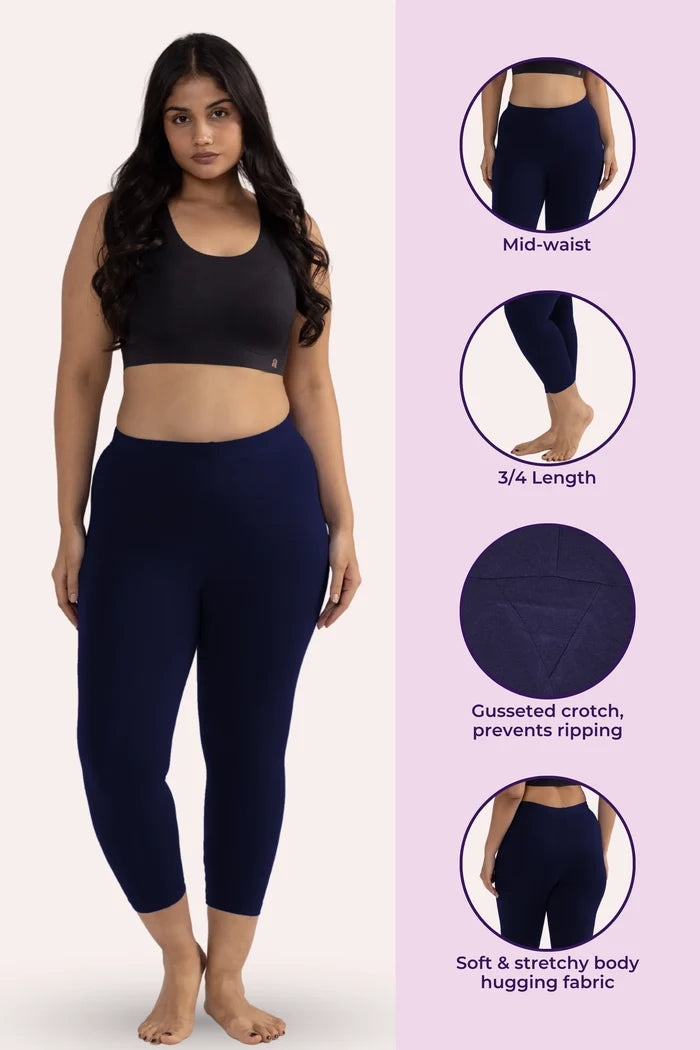 Woman wearing navy blue leggings with product features on a pink background