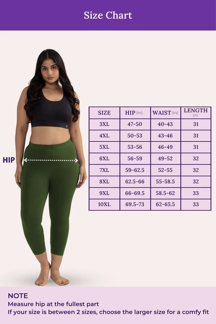 Woman wearing green leggings with a size chart on a white background