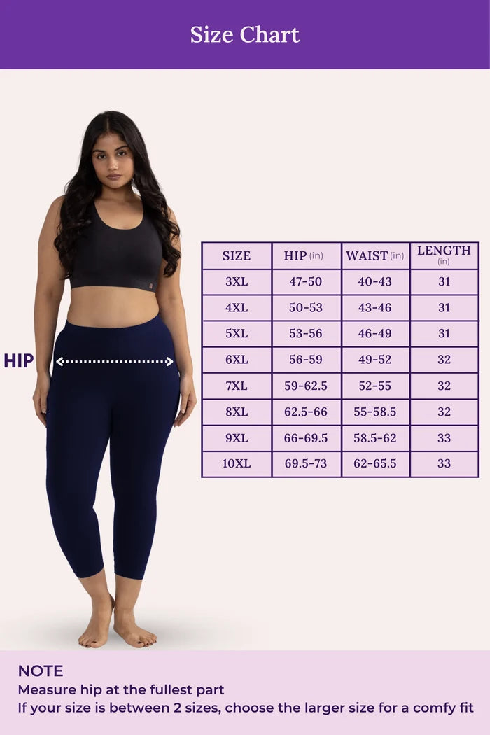 Woman wearing a black sports bra and navy blue leggings with a size chart on a purple background