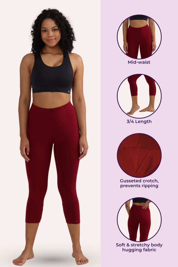 Woman wearing maroon cropped leggings with product features on a pink background