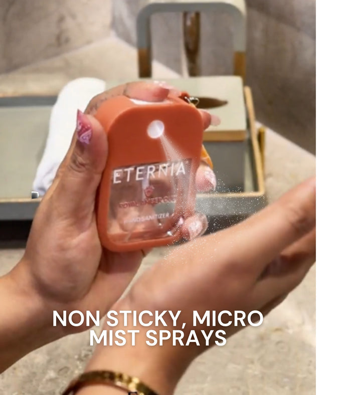 Orange hand sanitizer bottle held in hand with mist spray