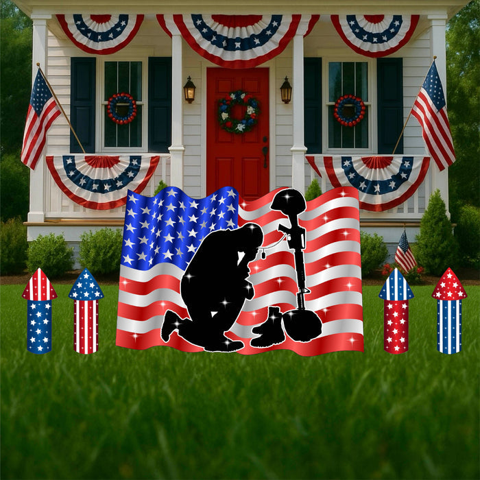 Patriotic yard art featuring a silhouette of a soldier with an American flag in the background, displayed in a front yard.