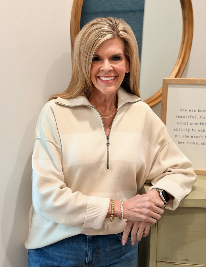 Woman wearing a white striped sweater against a plain background