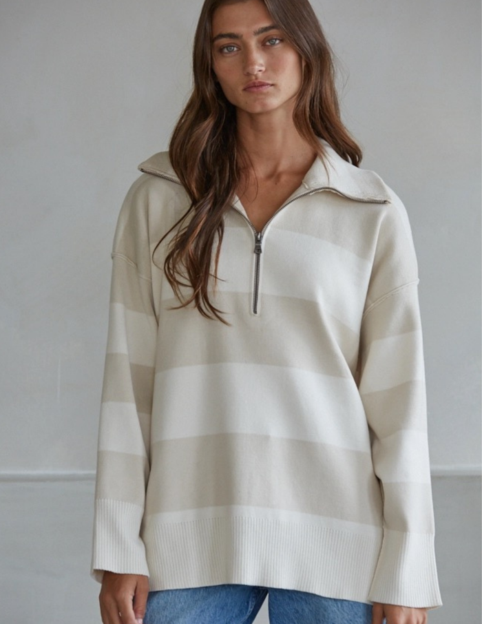 Woman wearing a white striped sweater against a plain background