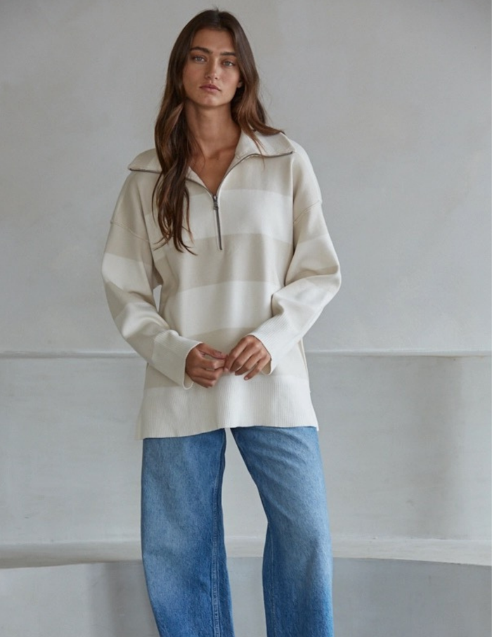 Woman wearing a white striped sweater against a plain background