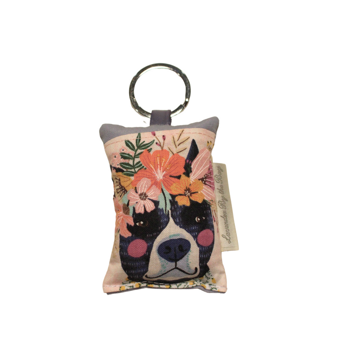 Dog with crown of flowers and red dots on its chicks design on embroidered key chain on white background