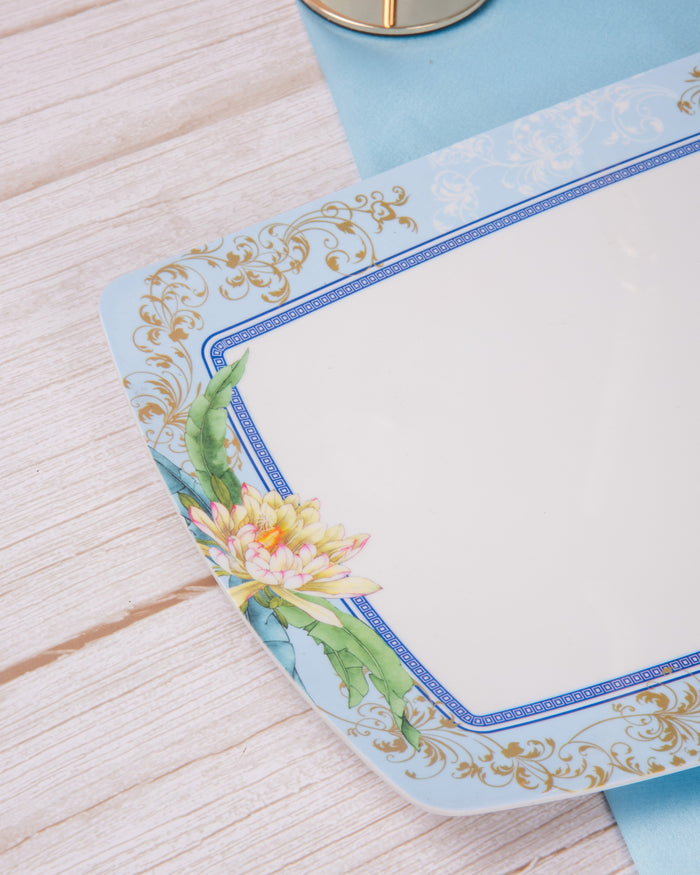 Rectangular serving plate corner with blue frame, gold scrollwork and floral print on white