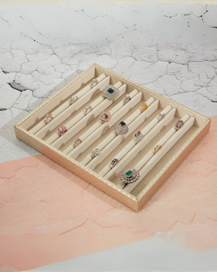 Beige jewellery display tray with cream dividers holding multiple rings