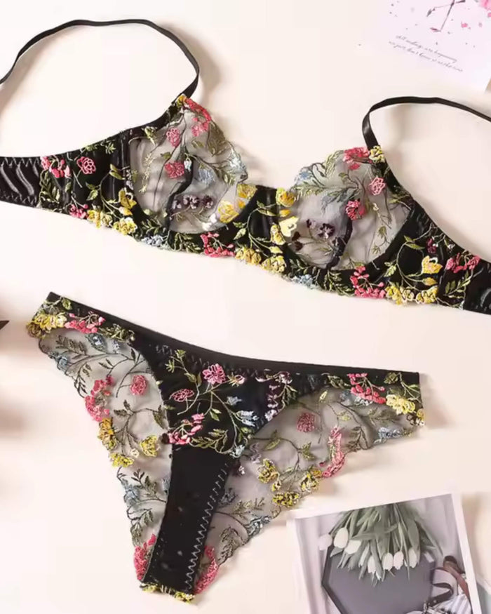 Floral embroidered bra and thong set, black lace with pink and yellow flowers, flat lay
