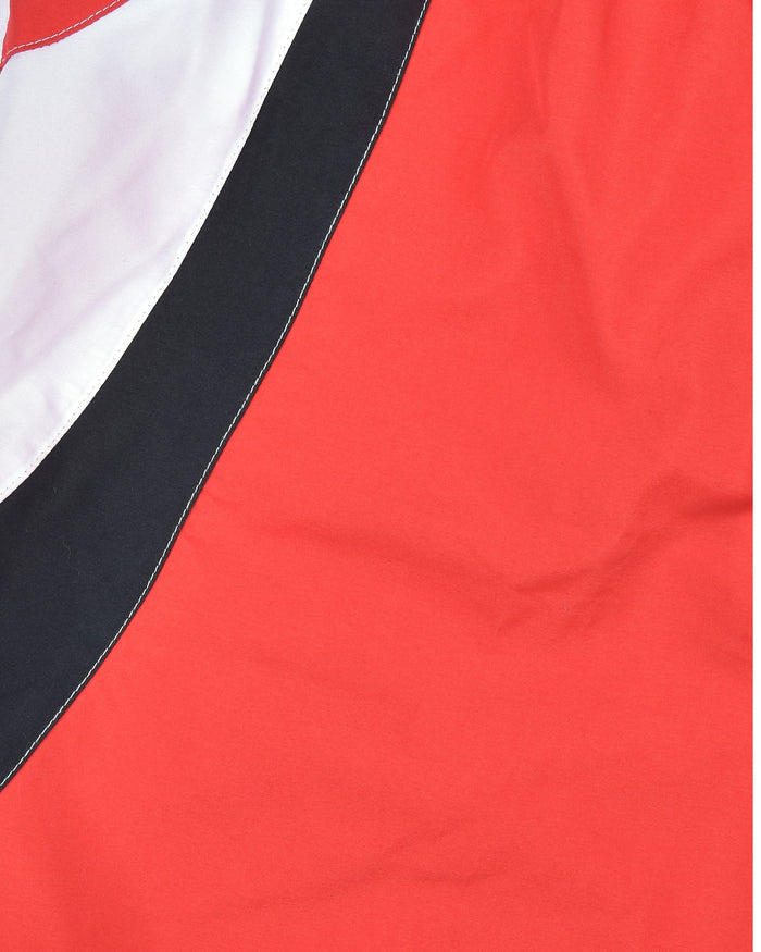Red swim shorts fabric close-up with black-and-white angled side panel
