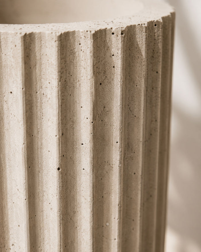 Off-white fluted concrete planter wall close-up with vertical ridges and speckled texture